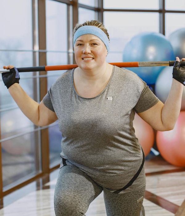 Smiling woman in sportswear enjoying a light cardio exercise indoors.